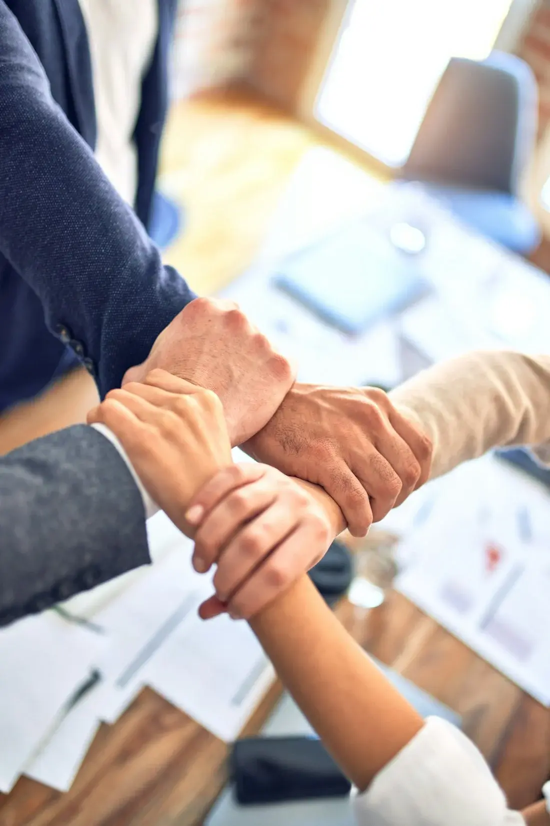 Colleagues holding each other's wrists in a gesture of teamwork
